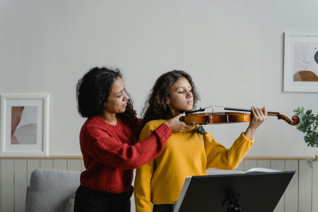 A woman teaching a girl to play violin